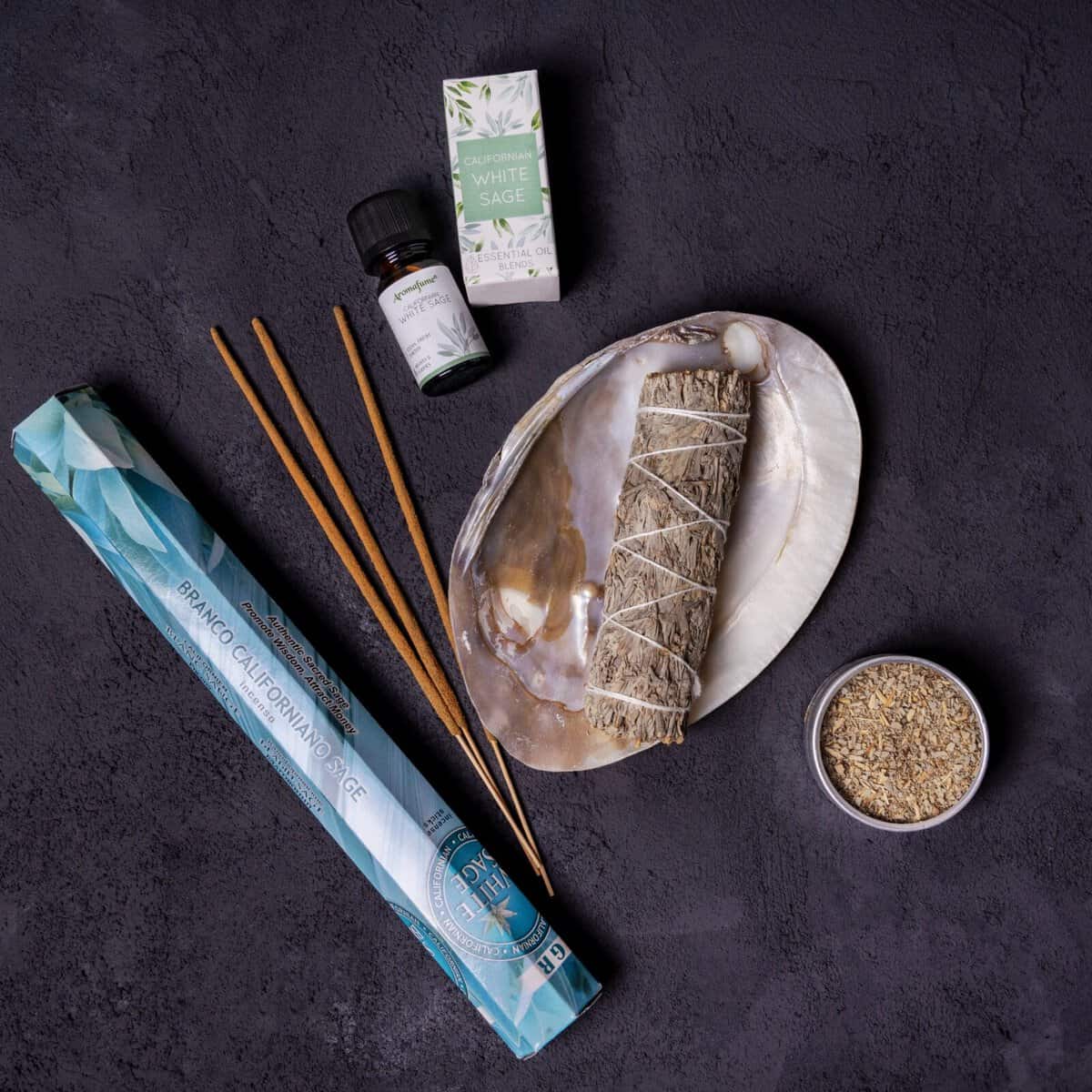 Set Salvie Albă include bețișoare de salvie albă, suport pentru bețisor, ulei esențial, o cutiuță și plante uscate, toate așezate elegant-ideal pentru curățare și purificare.
